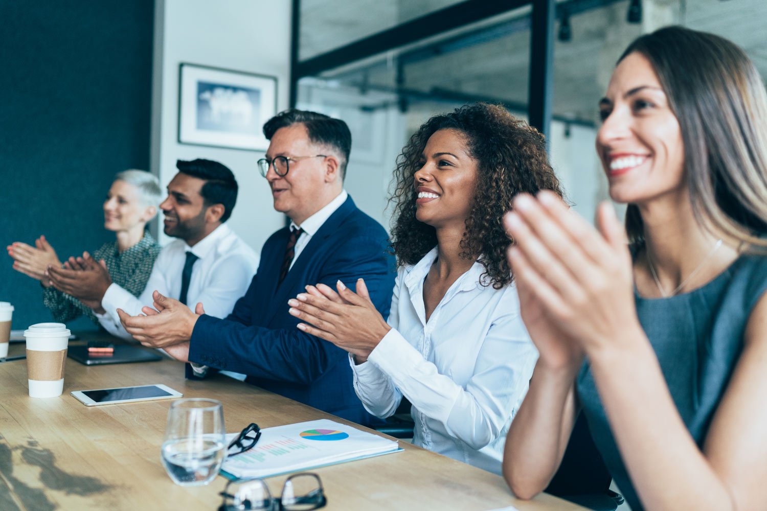 business people sit at a table clapping