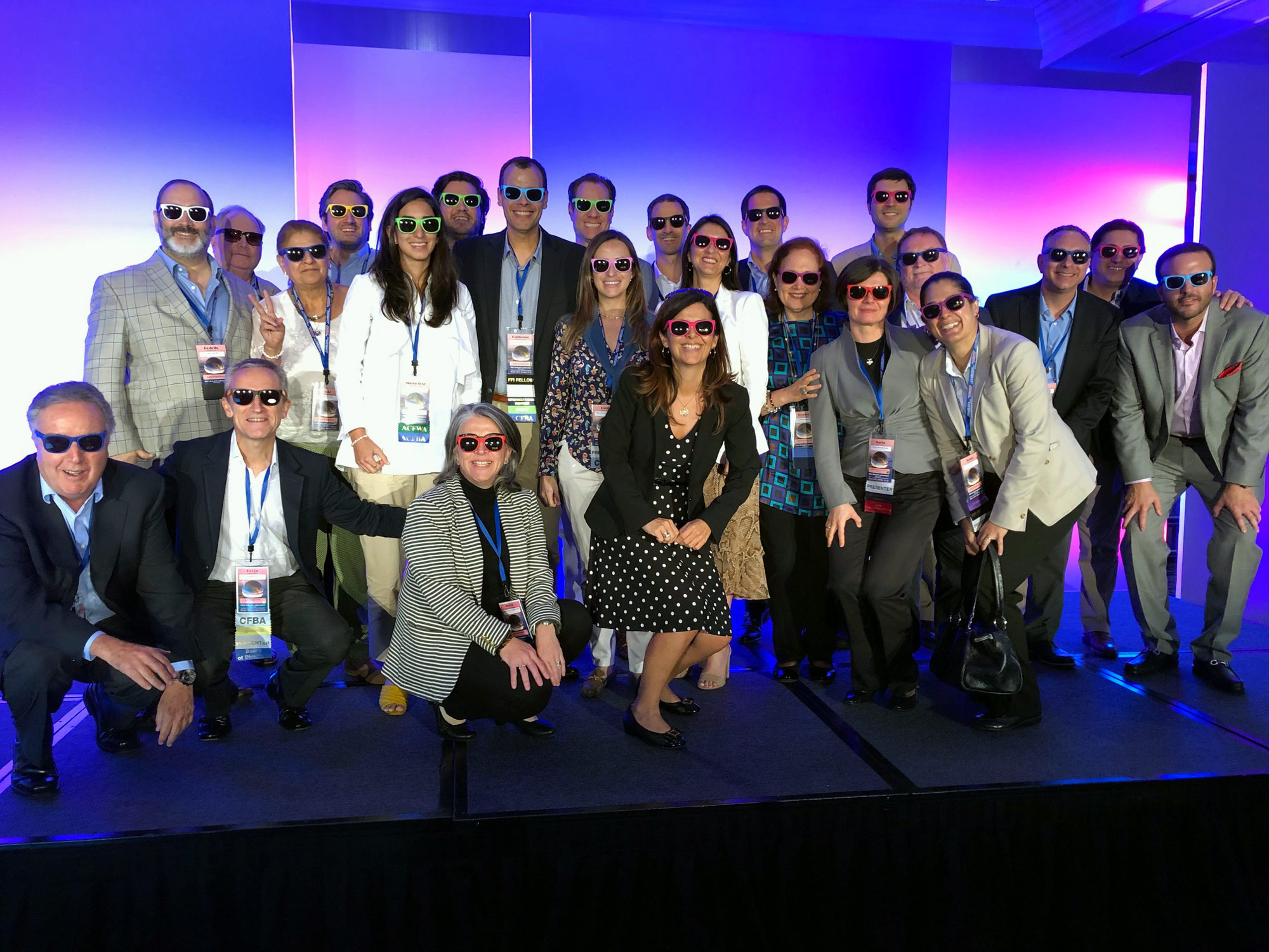 a large group photo of business people, smiling together, all wearing sunglasses