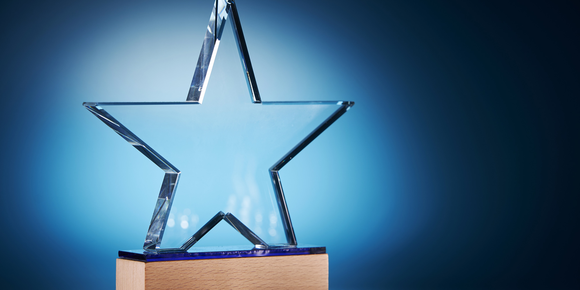 star shaped clear glass award with wood base