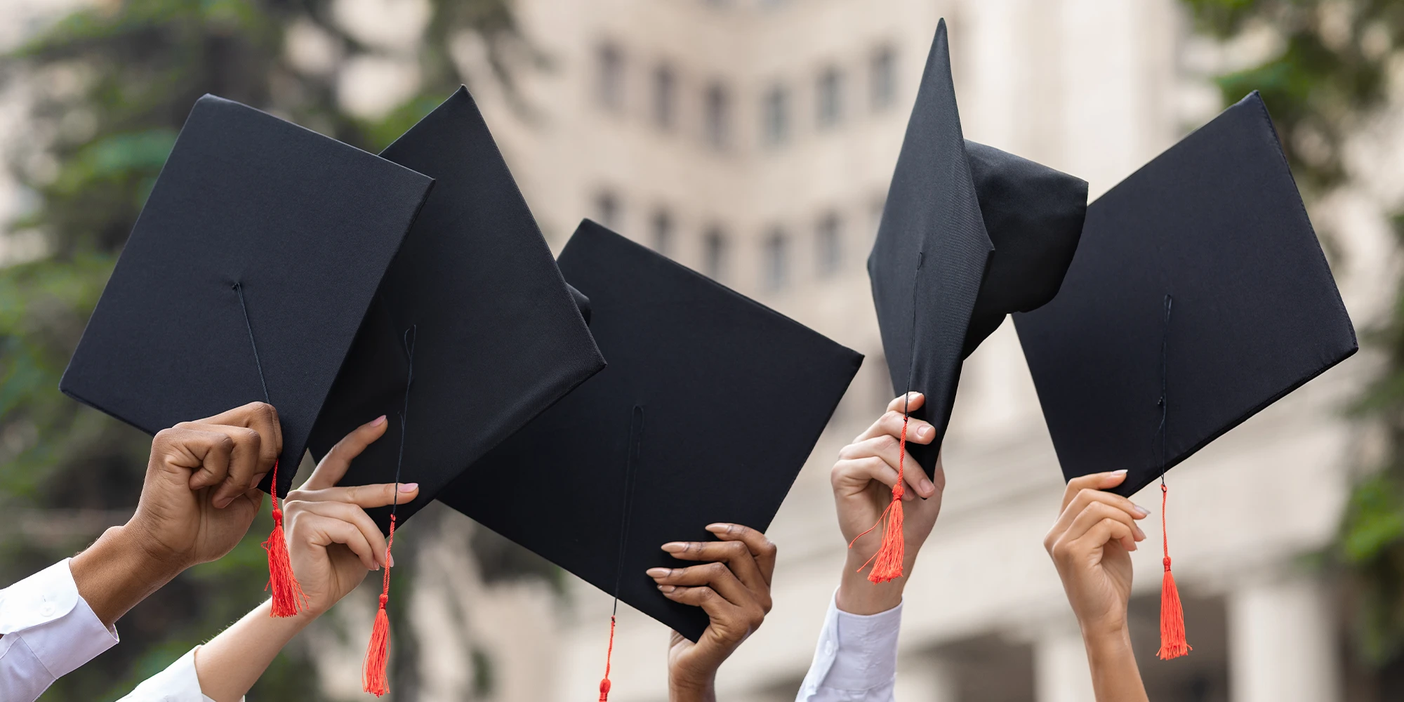 Cropped of multiracial group of students raising up hands with caps