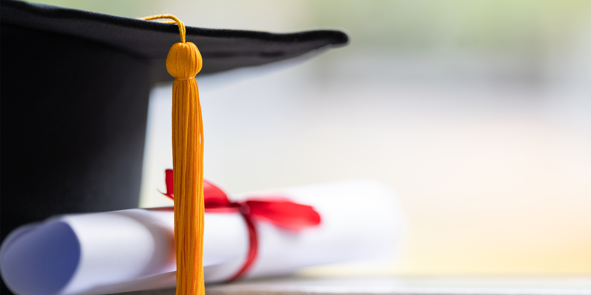 table with graduation cap and rolled up certificate with red ribbon