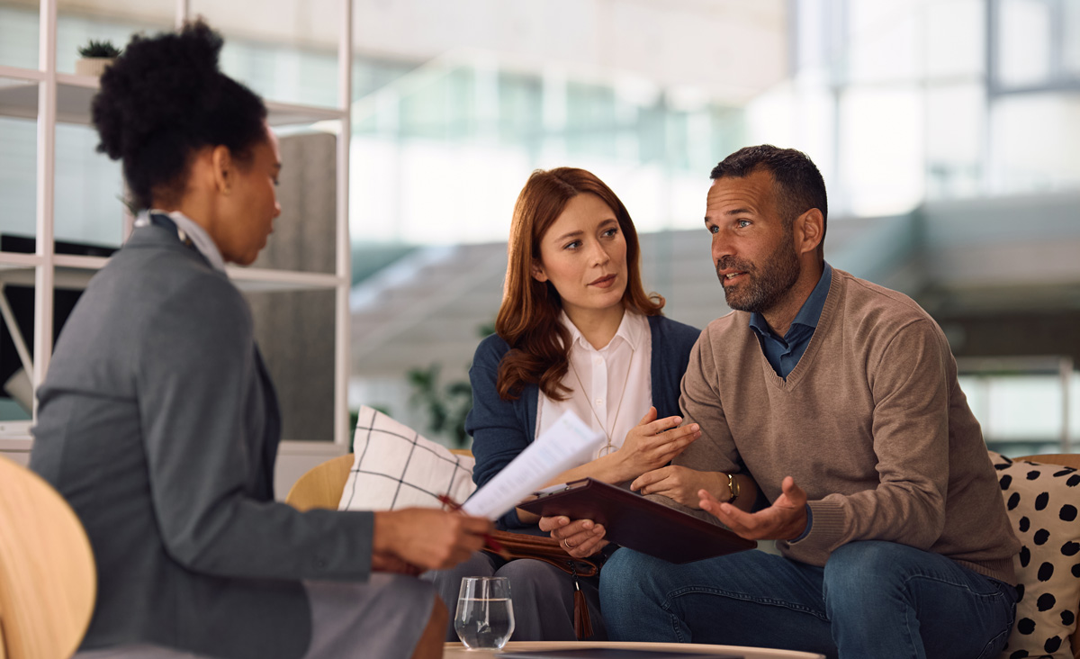 Couple talking to their financial advisor while analyzing paperwork in the office.