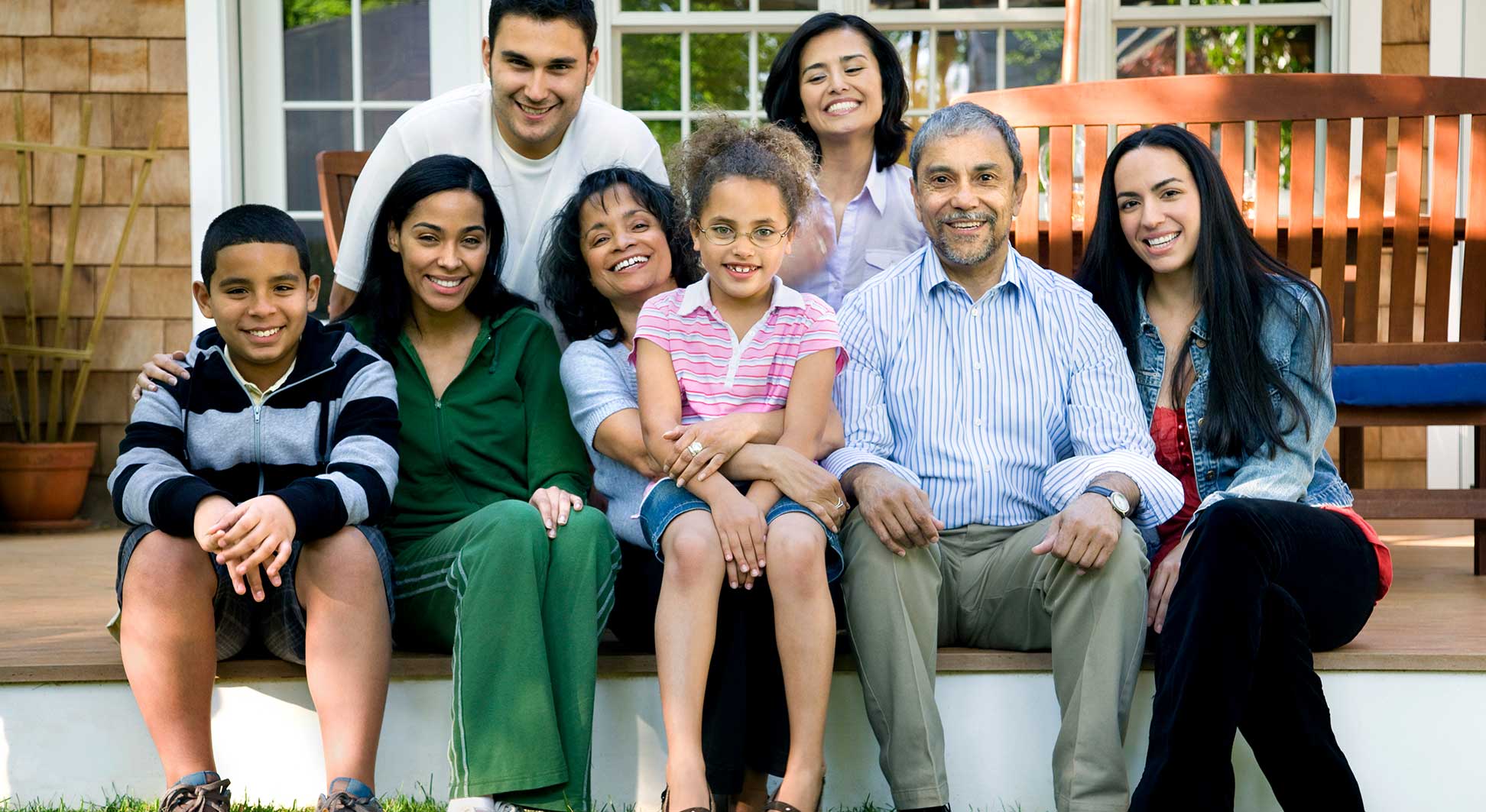A diverse family of eight poses together on a porch.