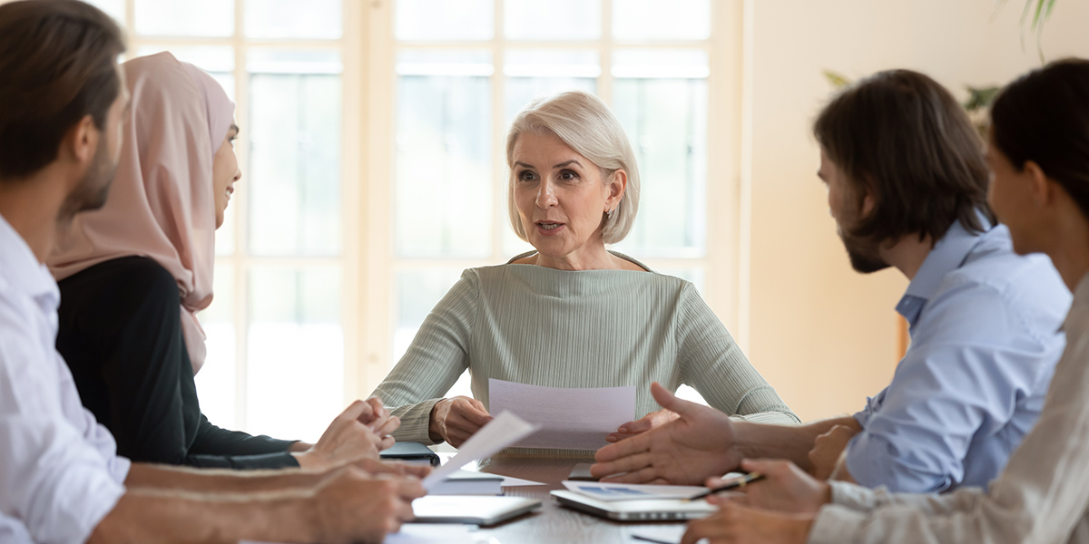 Middle aged businesswoman team leader holding corporate meeting with diverse employees